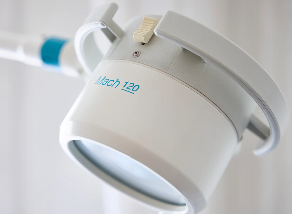 Nahaufnahme einer weißen medizinischen Leuchte mit grauen Henkeln an einem Arm