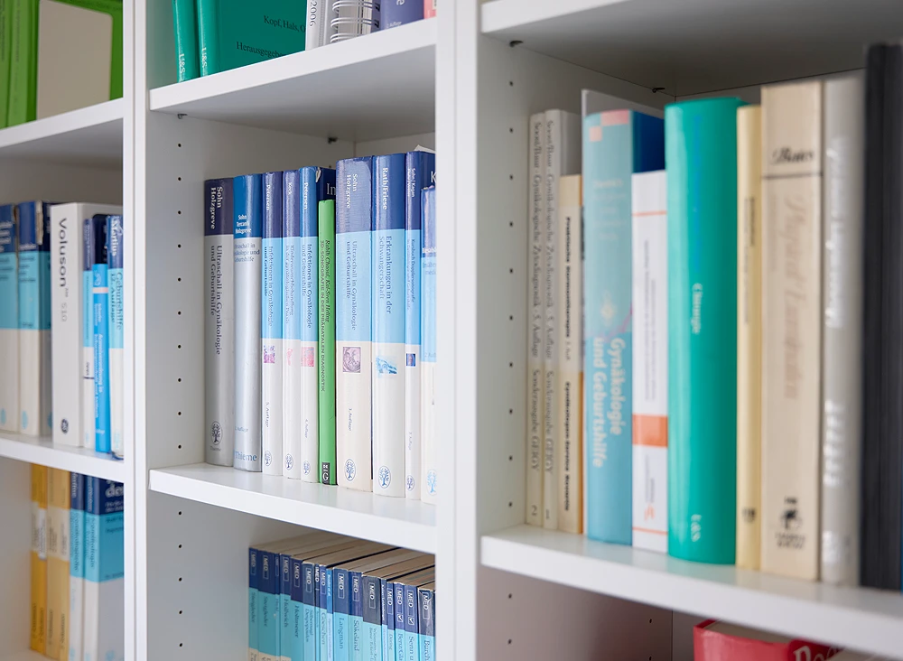 Nahaufnahme eines weißen Bücherregals mit medizinischer Fachliteratur